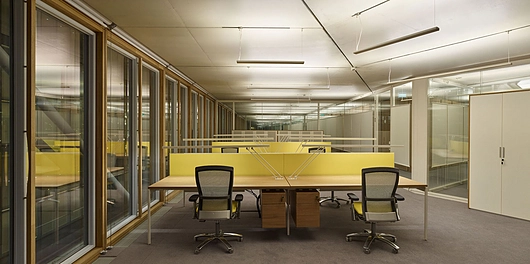 An office in the building making use of the lighting products specifically designed for the building seen hanging from the ceiling and on the desks. 